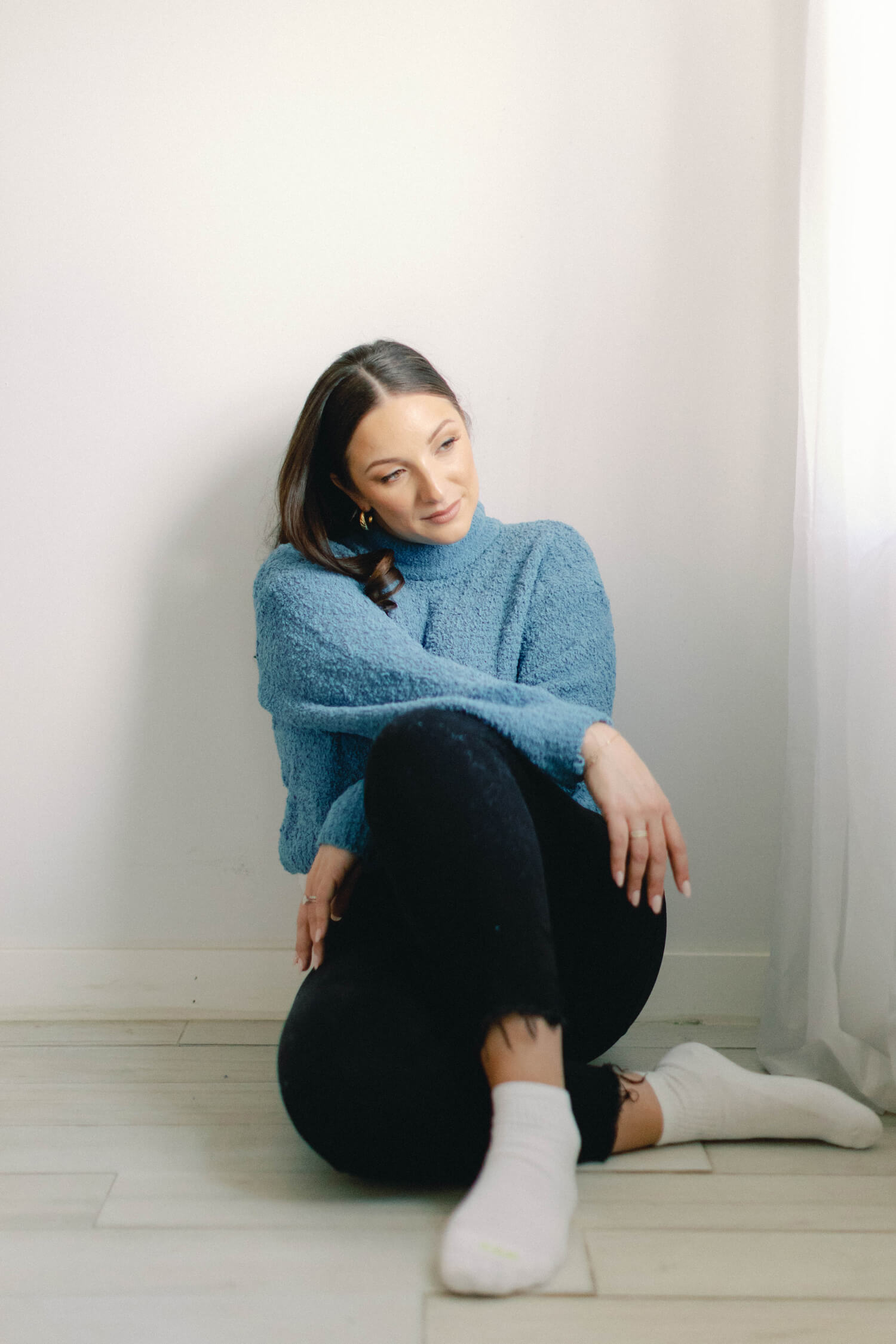 Magi sitting and wearing a blue sweater and black jeans.