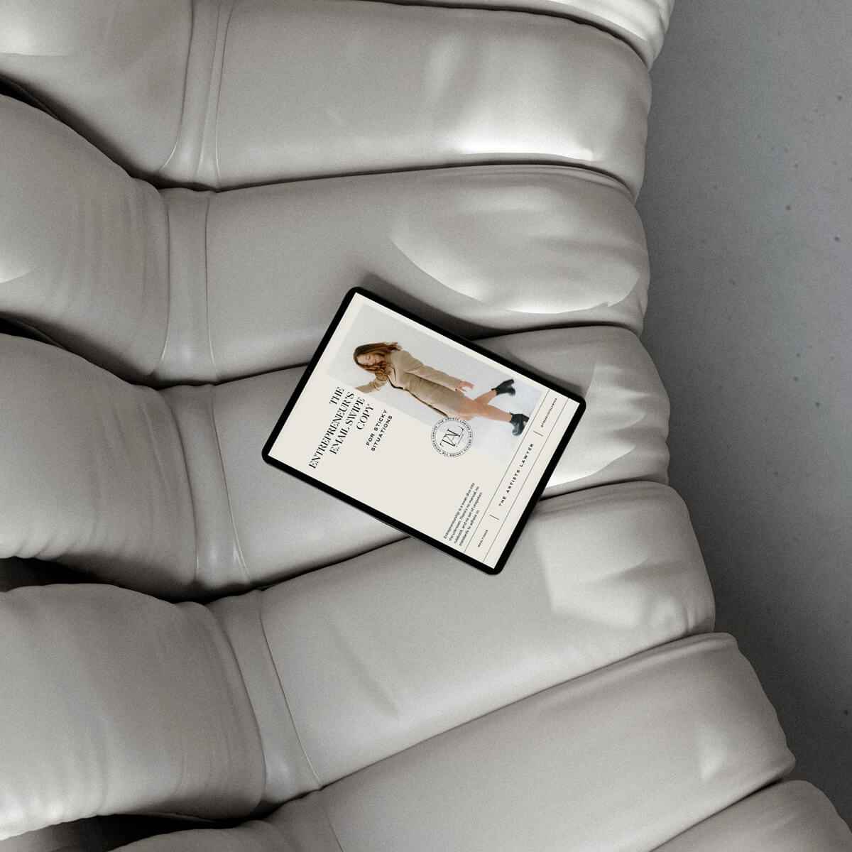 Ipad showing the entrepreneurs email swipe copy, laying on a beige couch.