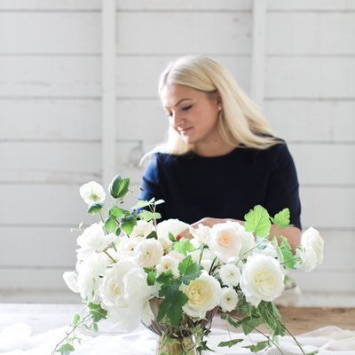Woman looking at a bouquet of white flowers.